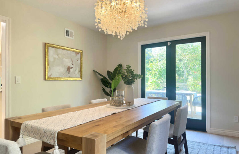 Close-up of a modern dining room setup in Westlake Village with a textured runner, statement chandelier, and greenery vase.