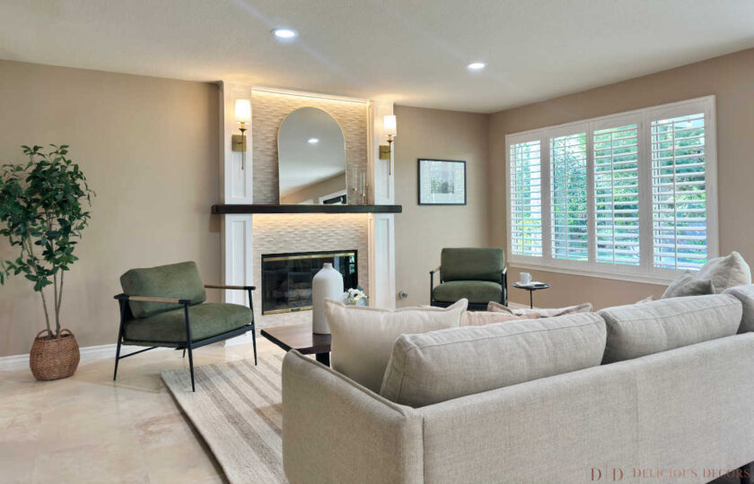 Cozy family room staged with a neutral sofa, olive green armchairs, a tile-accent fireplace, and white plantation shutters in Westlake Village.
