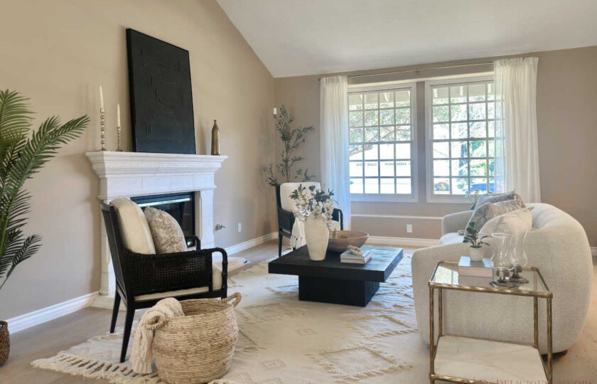Formal living room staged with black cane accent chairs, a black mantel artwork piece, and white sheer window drapery in Westlake Village.
