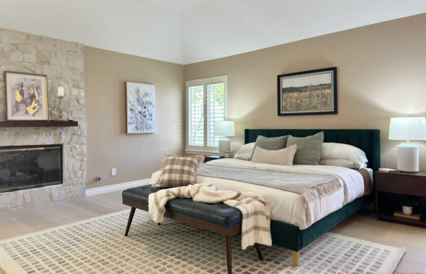 Westlake Village home staging in a luxury primary bedroom featuring a stacked stone fireplace, tufted green velvet bed, and geometric area rug.