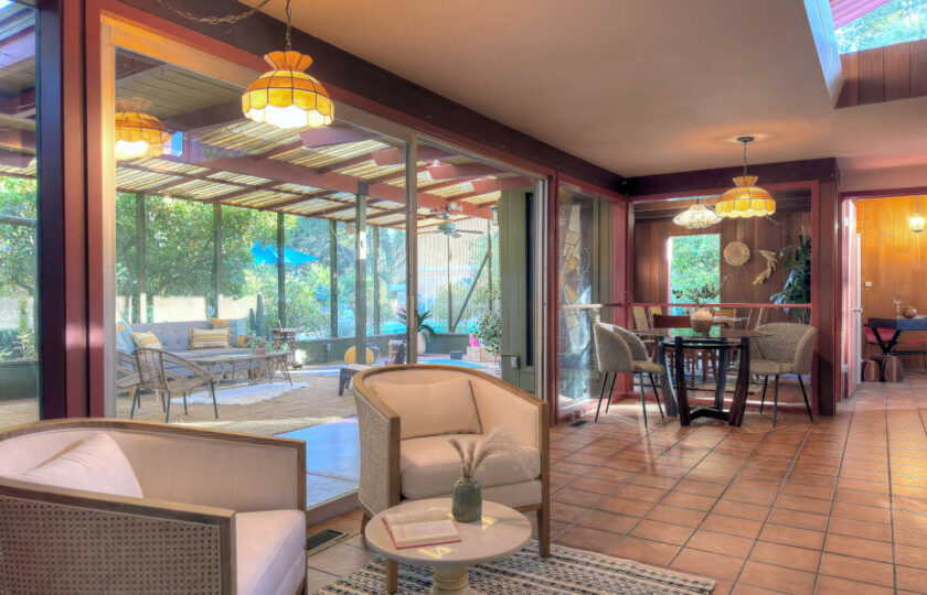 Mid-century modern ranch great room with wood paneling, terracotta tile floor, and custom staged seating area.
