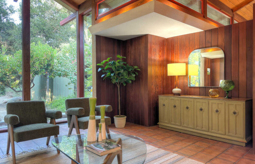 Vintage wood credenza and retro decor staged against rich wood wall paneling in an Ojai 1957 mid-century modern home.