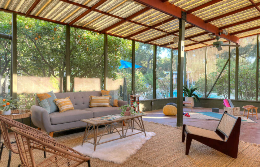 Covered sunroom patio staging with modern sofa, woven jute rug, and views into the surrounding Ojai landscape.