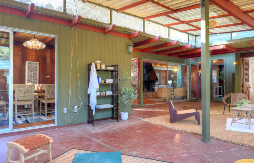 Indoor-outdoor living connection in an Ojai mid-century modern ranch featuring red concrete floors and sunroom staging.