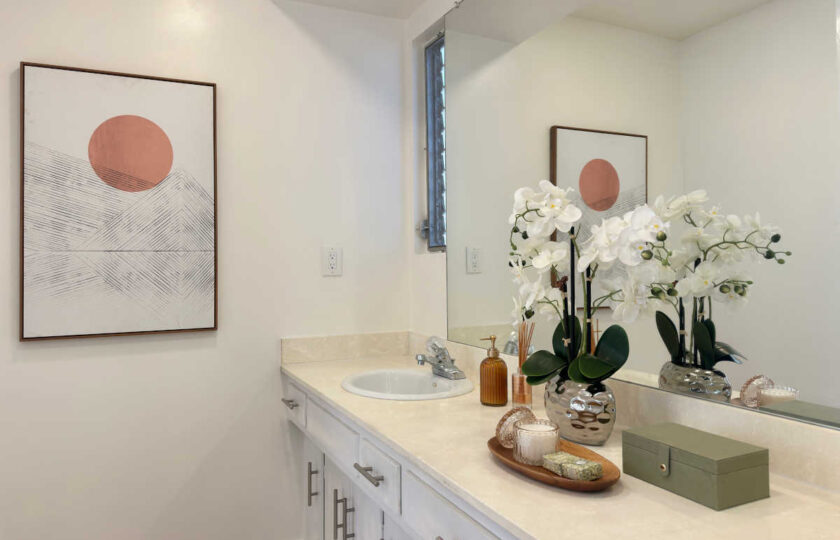 Woodland Hills MCM home staging featuring white vanity, large mirror, orchid, and warm sun and mountain art.