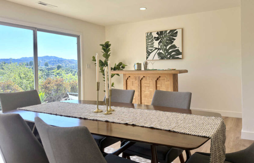 Woodland Hills MCM home staging showing walnut dining table, grey chairs, textured runner, and patio view.