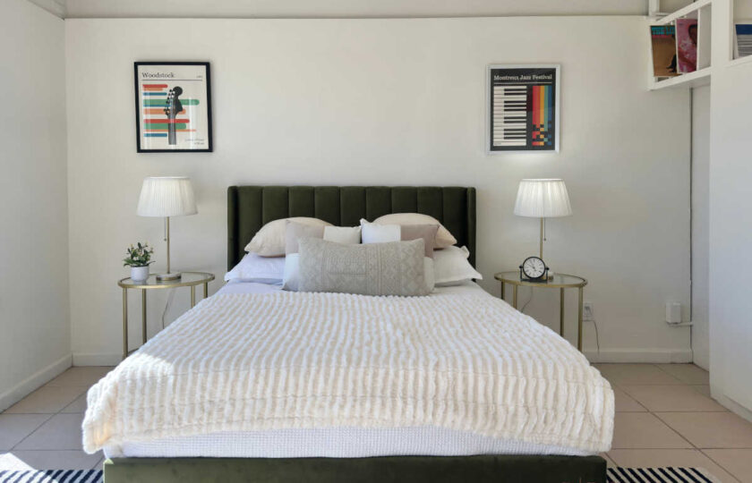Woodland Hills MCM home staging featuring green velvet headboard, white bedding, and retro music posters.