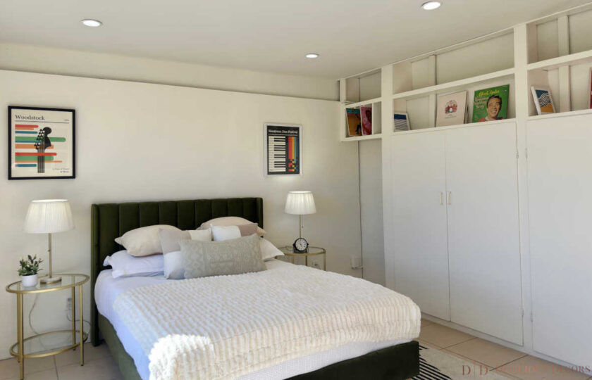 Woodland Hills MCM home staging with green bed, brass nightstands, white built-in closets, and vintage albums.