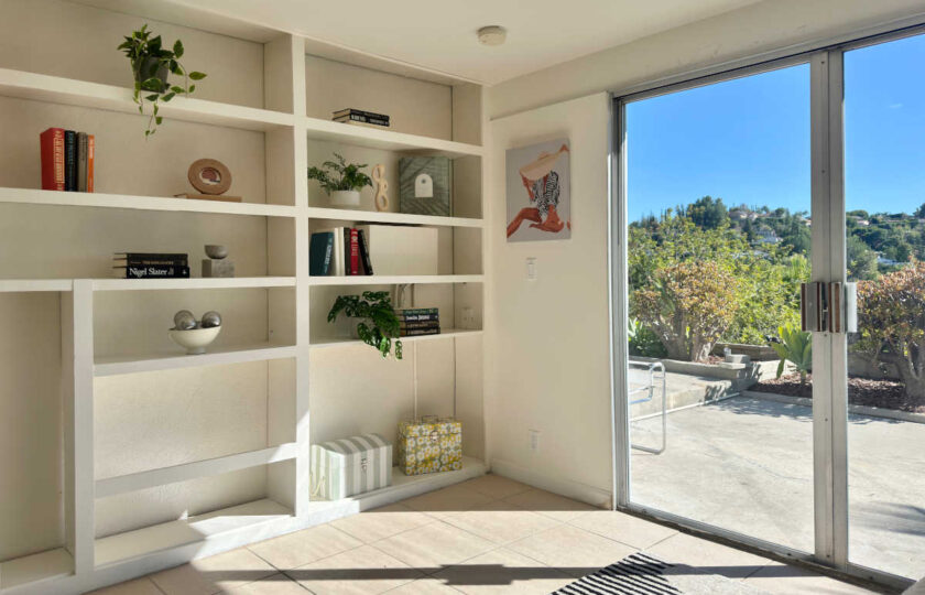 Woodland Hills MCM home staging featuring white built-in bookshelves, patterned rug, and patio door.