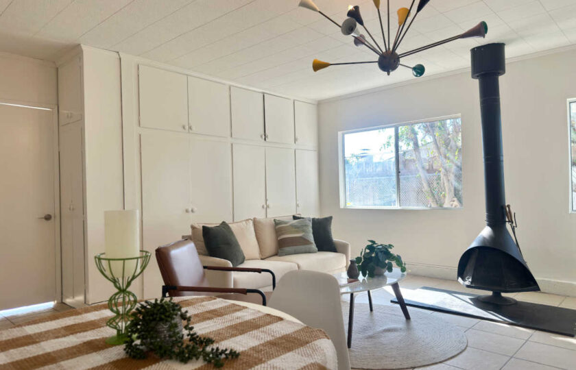 Woodland Hills MCM home staging showing white sofa, round marble coffee table, sputnik lighting, and fireplace.