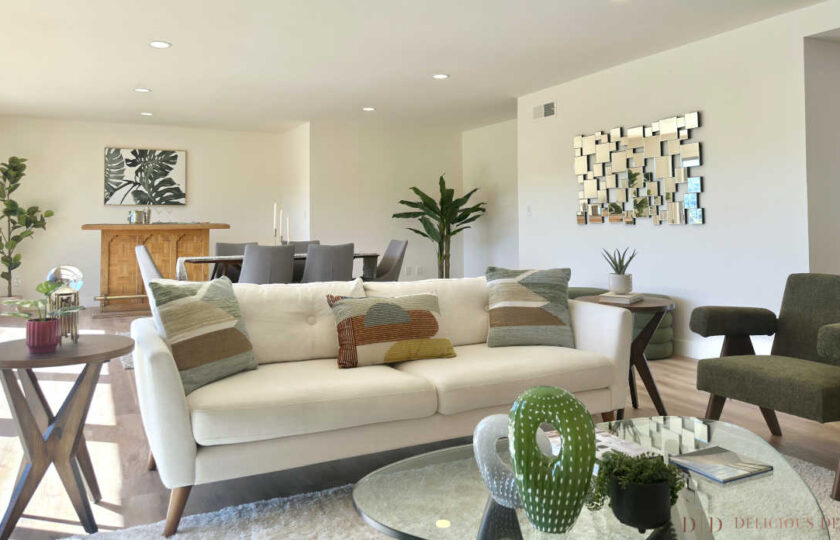 Woodland Hills MCM home staging showing a white tufted sofa, retro armchairs, art gallery, and bar in the background.